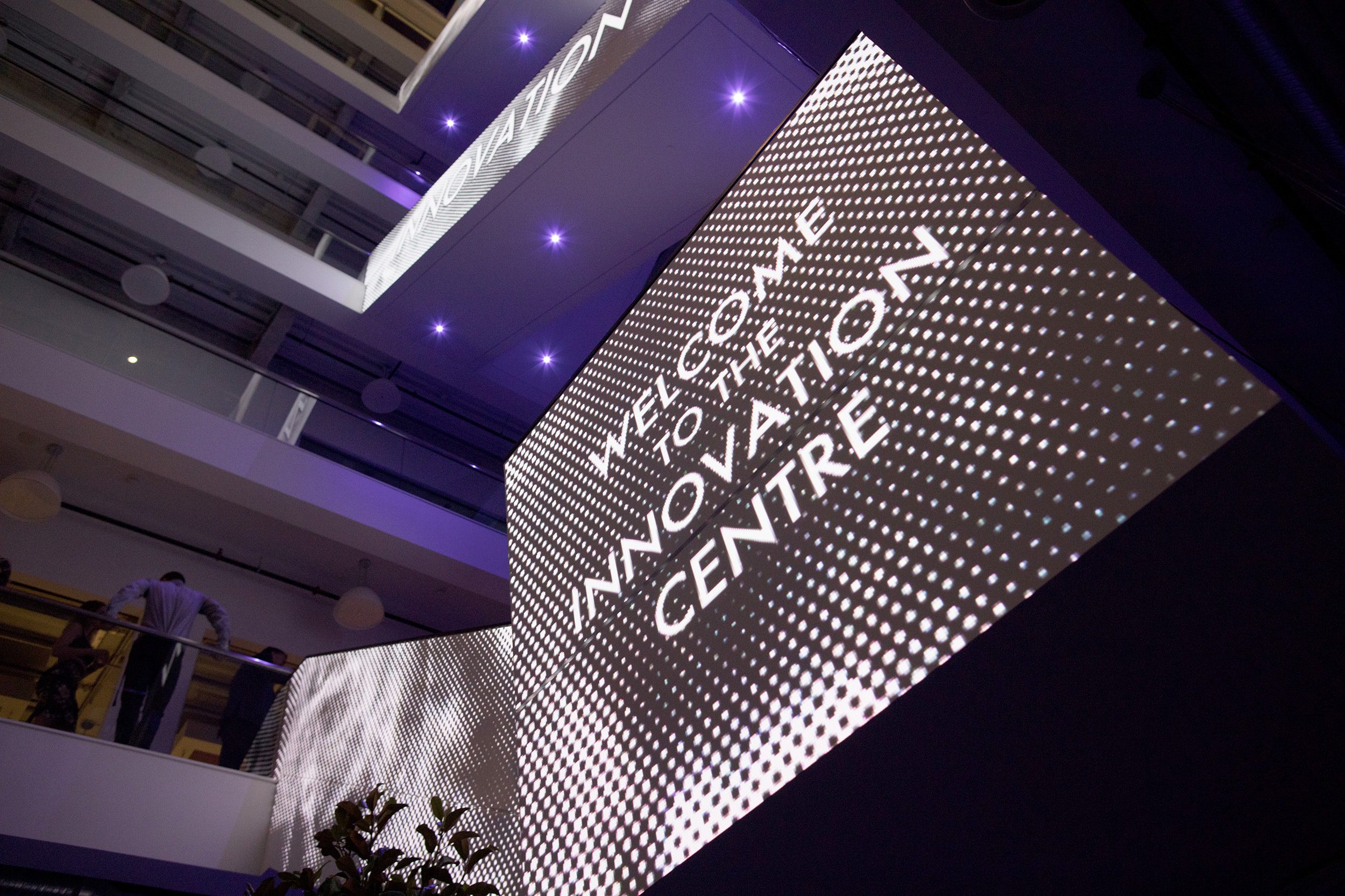 Projected image onto a wallspace in the atrium of the Kelowna Innovation Centre. It reads, "Welcome to the Innovation Centre." in uppercase white letters on a dotted white and black background.